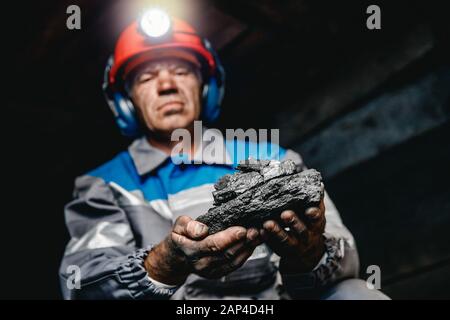 Il minatore mani sporche holding pezzo di miniera di carbone Foto Stock