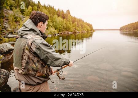 Fisherman spool di corda utilizzando la pesca a mosca canna nel fiume Foto Stock