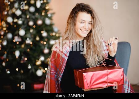 La ragazza libera inchinarsi sul regalo di anno nuovo, il wrap rosso, sullo sfondo è albero. Concetto di Natale Foto Stock