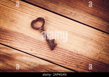 Vecchio arrugginito chiave vintage a forma di cuore, uno sfondo di legno. Amore e il giorno di San Valentino biglietto di auguri Foto Stock