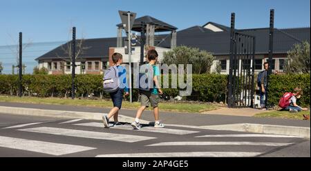 Due scolari che attraversano la strada su un passaggio pedonale