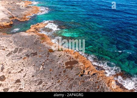 Vista dall'alto mare azzurro con onde che battono sulla spiaggia e sulle rocce. Foto aerea. Foto Stock
