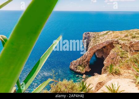 Grotta Azzurra A Malta. Una barca da diporto con i turisti. Finestra ad arco naturale in roccia Foto Stock