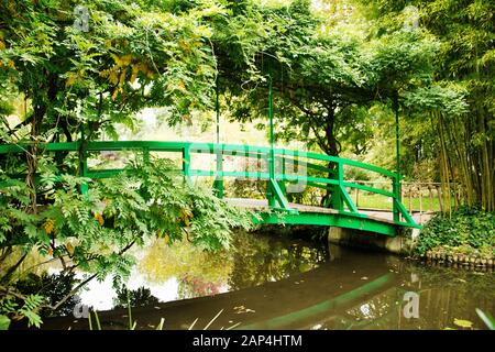 Giardino Di Claude Monet Giverny. Ponte giapponese con alberi in primo piano e ponte di copertura Foto Stock