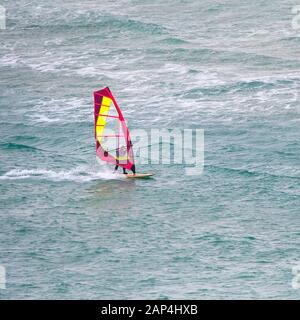 Una scrematura windsurfista in velocità sul mare a Crantock a Newquay in Cornovaglia. Foto Stock