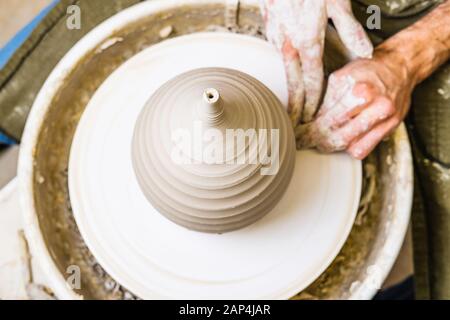 Potter lavorando sulla ruota del vasaio con argilla grezza con le mani, facendo nuova ciotola, concetto di piccola arte di affari Foto Stock