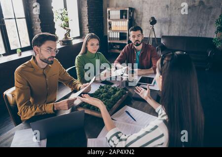 Azienda di quattro buon attraente messo a fuoco esperti del direttore esecutivo di businesspeople seduti intorno al tavolo che discute la strategia di innovazione a. Foto Stock