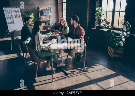 Foto a tutta lunghezza del gruppo persone sedersi tavolo da tavolo hanno briefing discutere di sviluppo aziendale uomo suggeriscono grandi progressi idee in ufficio moderno Foto Stock