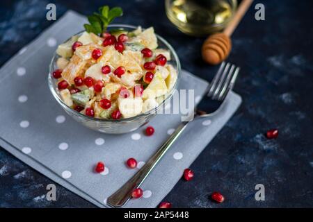 La dieta insalata di frutta per colazione. Kiwi orange banana e mela tagliata a cubetti e condita con yogurt con il miele. Cibo sano, il vegetarianismo. Su un backgro scuro Foto Stock