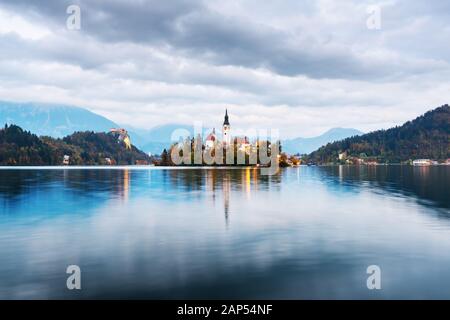 Pittoresca vista autunnale del lago di Bled nelle Alpi Giulie, Slovenia. Isola con la Chiesa del pellegrinaggio dell Assunzione di Maria su sfondo. Fotografia di paesaggi Foto Stock