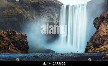 Da solo turista che si affaccia a cascata Skogafoss, Islanda Foto Stock