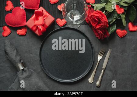 Cena romantica di San Valentino o di compleanno. Romantico tavolo con champagne, rosa rossa su tovaglia di lino nero. Vista dall'alto. Foto Stock