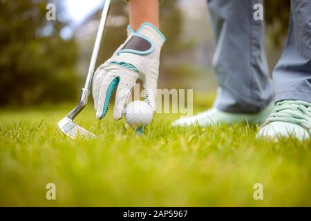 Mano nel guanto posizionando la pallina da golf sul raccordo a T Foto Stock