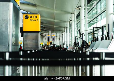 Londra, Aeroporto di Heathrow, ago 2019: Segnali gialli illuminati all'aeroporto con numero di gate. Passeggeri in attesa di imbarco Foto Stock