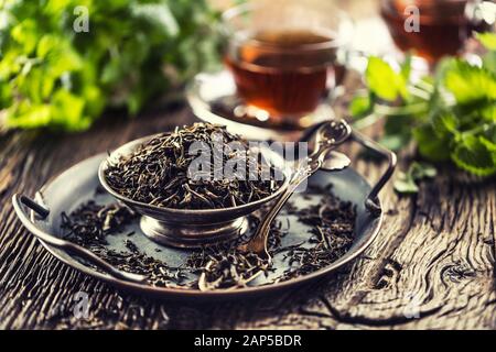 Essiccate le foglie di tè nella ciotola sulla tavola in legno rustico Foto Stock