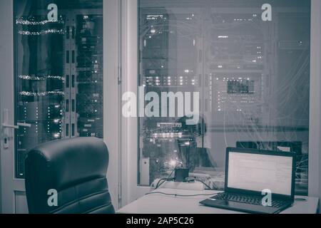 Foto in bianco e nero di un amministratore di sistema del luogo di lavoro vuoto nella sala server. Molti rack con apparecchiature per computer Foto Stock