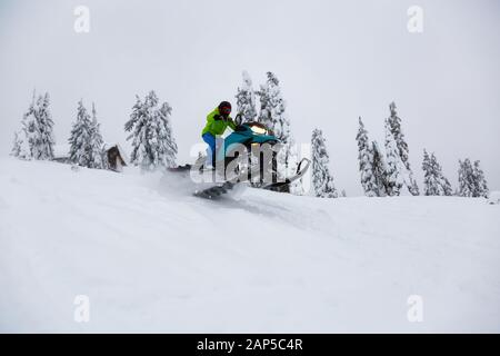 Uomo avventuroso in sella ad una motoslitta nel bianco della neve Foto Stock