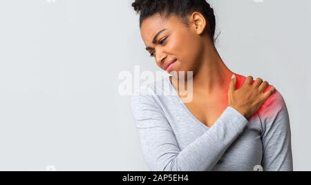 Ragazza triste che ha un forte dolore alla spalla, massaggiando la zona dolorosa Foto Stock