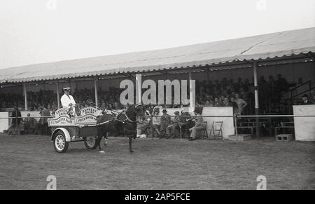 1950s, storico, in una fiera di campagna inglese, il Thame Show, gli spettatori seduti in uno stand guardare come un milkman parades in un vintage open-top trainato da cavalli, Oxford, Inghilterra, Regno Unito. Foto Stock