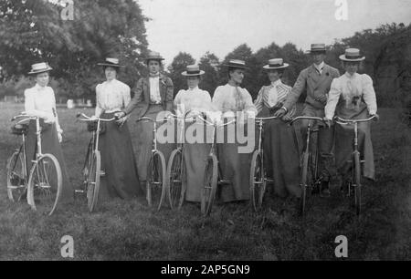 C 1900s, storico, un gruppo di donne che indossano cappelli di paglia e abiti lunghi in piedi insieme in un campo con le loro biciclette, Inghilterra, Regno Unito. In quest'epoca, il ciclismo era una popolare attività di svago per adulti e le loro macchine erano conosciute come biciclette di 'sicurezza', a causa delle dimensioni inferiori delle ruote rispetto alla ruota alta o penny-farthings della tarda epoca vittoriana e le loro gomme gonfiate pneumatiche. L'invenzione della bicicletta di sicurezza è stata uno sviluppo radicale per le donne, dando la libertà fuori casa e svolgendo un ruolo chiave nella loro liberazione come ha dato loro la mobilità personale e l'indipendenza. Foto Stock