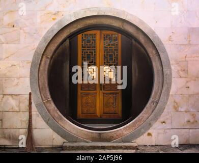 Arco di pietra circolare e porta di legno in un tempio buddista cinese a Saigon, Vietnam. Foto Stock