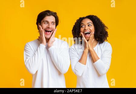 Scioccato coppia interracial esclamando e toccando guance in stupore Foto Stock