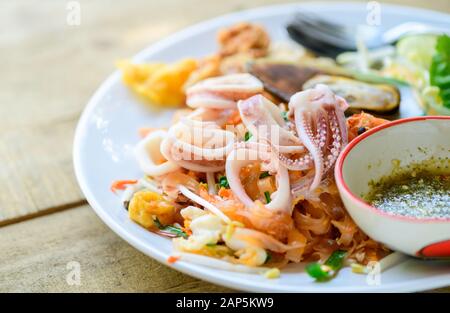 Calamari su tagliatelle di riso fritte (Pad Thai) con cozze. Piatti nazionali della Thailandia, popolare cibo tailandese Foto Stock