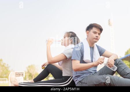 Ritratto di una bella coppia ispanica bere acqua e riposare dopo il runnng in pista a studium, Sano e concetto di sport Foto Stock