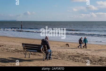 Bournemouth Beach con Dog Walkers in inverno e una persona seduta da sola. Foto Stock