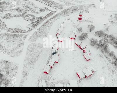 Vista panoramica dei colorati edifici in legno con vista dall'alto. Villaggio di pescatori e città turistica. Case rosse di legno del villaggio di pescatori in nevoso coperto in inverno. Foto Stock