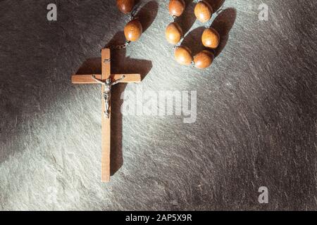 In legno antico rosario francescano, sulla grande croce cristiana Gesù, un  raggio di sole illumina il rosario su una pietra grigio Sfondo, religiosi e  f Foto stock - Alamy