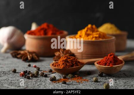 Ciotole con spezie e ingredienti su sfondo grigio, primo piano Foto Stock