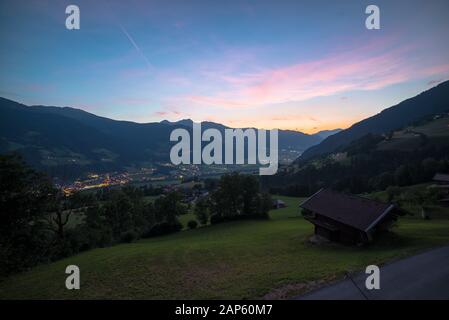 Nuvole rosa sulle Alpi dopo il tramonto. Le luci delle case nella valle sottostante sono visibili. Foto Stock