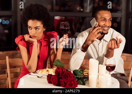 La Donna Si Annoiò Aspettando Il Ragazzo Che Parlava Su Cellphone Nel Ristorante Foto Stock