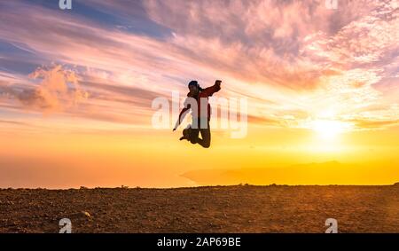 Uomo felice salti di gioia al tramonto. Il successo, vincitore, felicità, ttavel concetto. Foto Stock