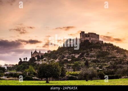 Tramonto dietro il castello di Sant Salvador e Transfiguracio del Senyor chiesa, città di Arta, Maiorca Foto Stock