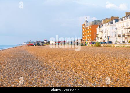 Deal England - 19 agosto 2019; Vista lungo la spiaggia di pietra rossa con barche da pesca vecchio stile tirato su e Beach Street edifici all'alba Foto Stock