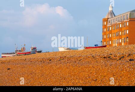 Deal England - 19 agosto 2019; Vista lungo la spiaggia di pietra rossa con barche da pesca vecchio stile tirato su e Beach Street edifici all'alba Foto Stock