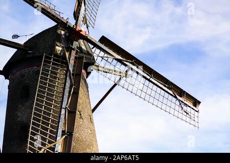 Vista ravvicinata e a basso angolo delle ali e della torre di mattoni in pietra dell'antico mulino a vento tedesco - Xanten, Germania (Krimhildmuehle) Foto Stock
