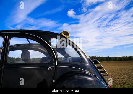 Viersen, Germania - 12 Ottobre. 2019: Vista laterale su una classica vettura setta nera francese 2CV con tetto a scomparsa aperto contro il cielo blu nell'area rurale Foto Stock