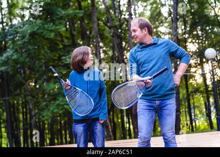 Padre figlio insegna a giocare a badminton nel parco. Week-end per due persone. Foto Stock