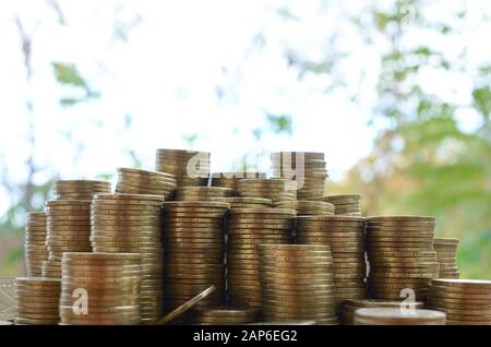 Grande quantità di vecchi e luminosi ucraini 1 pile di monete di hryvnia primo piano su tavola di legno su sfondo verde sfocato alberi. Il concetto di business e ricco l Foto Stock