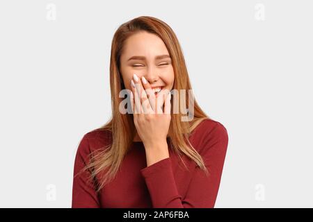 La ragazza ride ad alta voce copre la bocca la mano chiude gli occhi Foto Stock