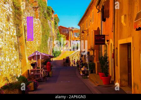 Roussillon En Provence, Francia - 2 Ottobre. 2019: Vista sulla strada con pareti in pietra naturale della fortezza e case gialle francesi color ocra del mediterraneo agai Foto Stock