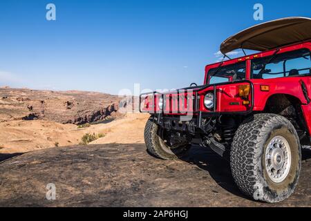 Un H1 Hummer parcheggiato su una collina di arenaria che guarda sul fiume Colorado su una 4x4 tour sul Hell's Revenge Trail in Sandflats Recreation Area Foto Stock