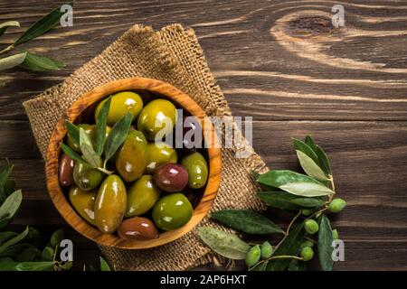 Olive nere e verdi su un tavolo di legno. Foto Stock