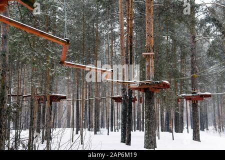 Parco avventura Treetop in una foresta invernale innevata Foto Stock