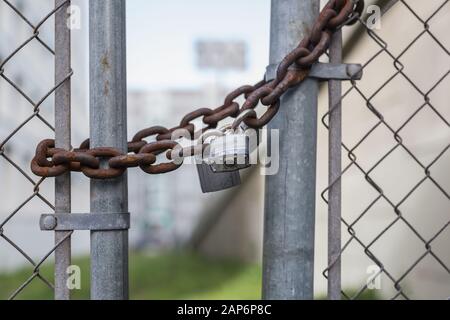 Catena arrugginita con lucchetto su una recinzione chiusa Foto Stock