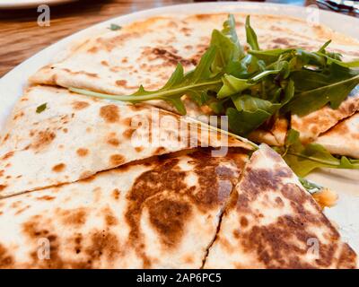 Pollo Quesadilla con foglie di rucola su piastra bianca Foto Stock