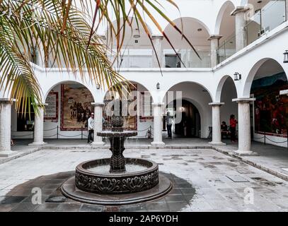 San Pedro Cholula, Messico, 17 ottobre 2018 - Colonnata con archi, fontana e palme nella piazza interna del municipio di San Pedro Cholula. Foto Stock